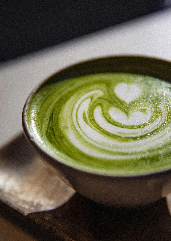 Filiżanka kremowej matcha latte z dekoracyjnym wzorem serca z mlecznej pianki.